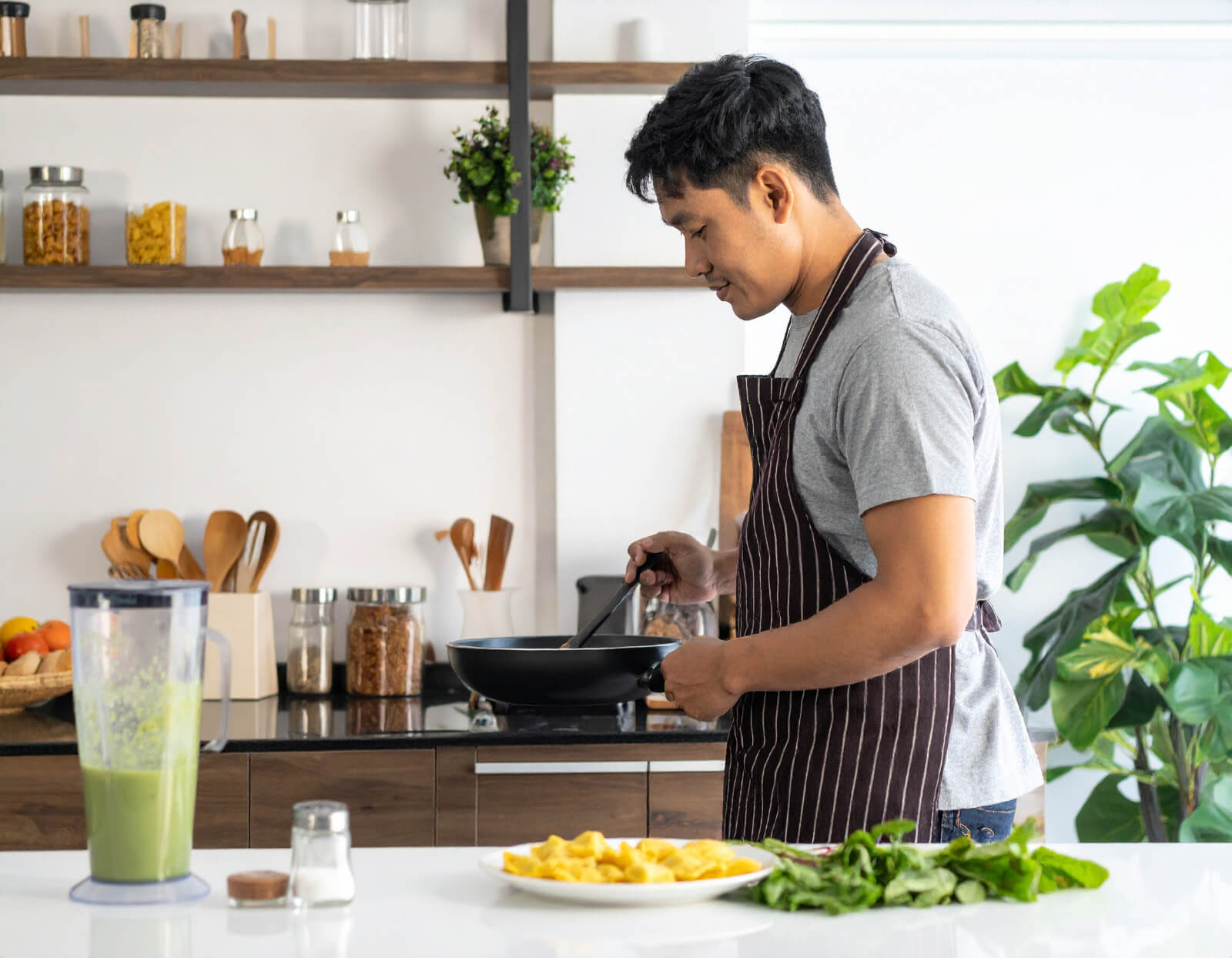 Homme cuisinant dans une cuisine moderne, versant de l’huile de CBD dans un plat, illustrant l’utilisation culinaire du CBD et le bien-être au quotidien.