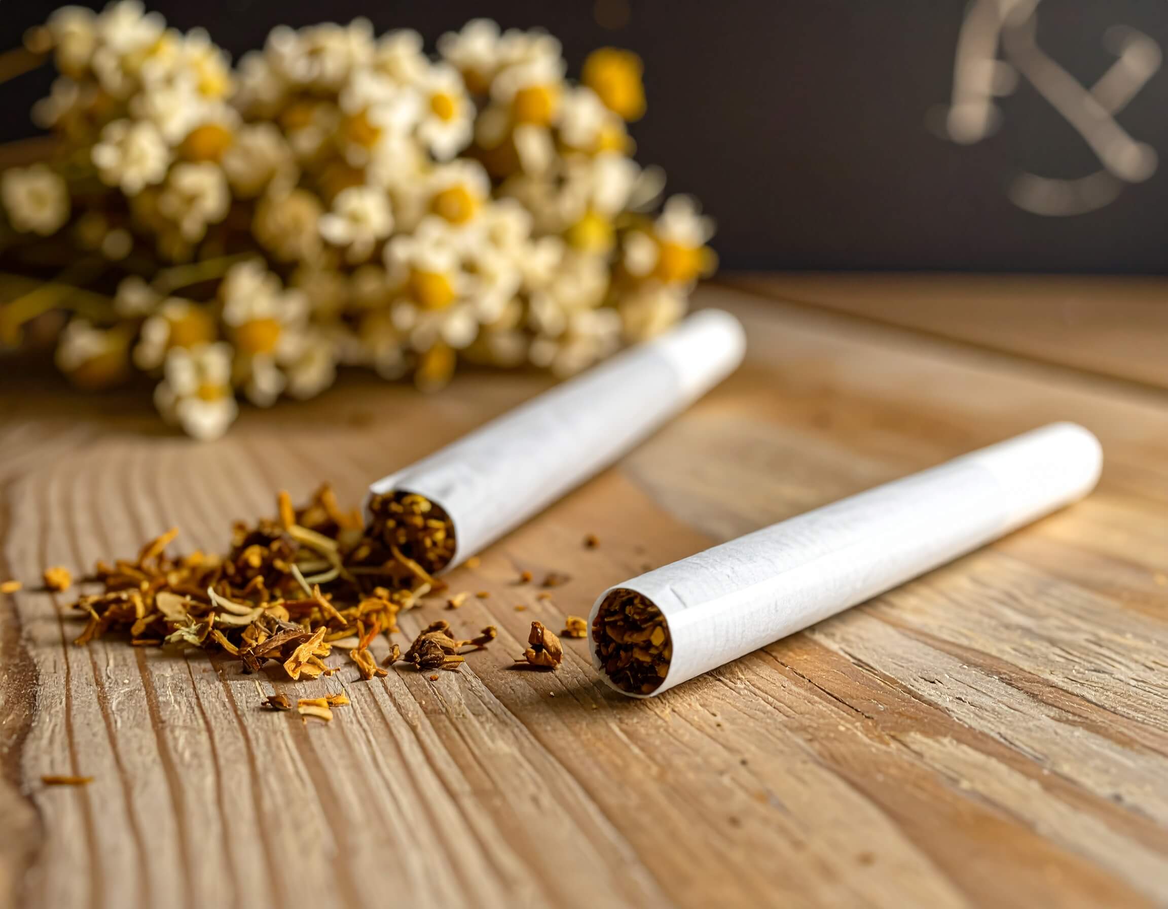 Deux joints de CBD posés sur une table en bois, lumière naturelle et ambiance détente.